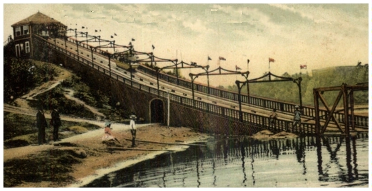 (Image: A Boat Descends the Ramp while Four People Look Toward the
 Landing Area)